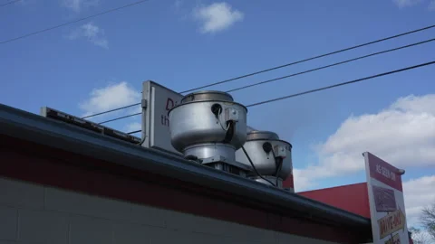 Restaurant rooftop ventilation fans under blue sky at roadside diner 库存影片 334443411
