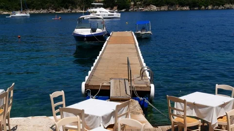 Restaurant by the sea with white table set and Wood pier and a motor boat Stock Footage 113138108