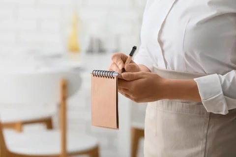 Restaurant server taking an order with a pen and notepad, hospitality and cus Stock-Fotos
