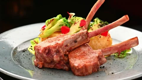 Restaurant serves grilled lamb chops with vegetables on a plate Stock-Footage 328374565