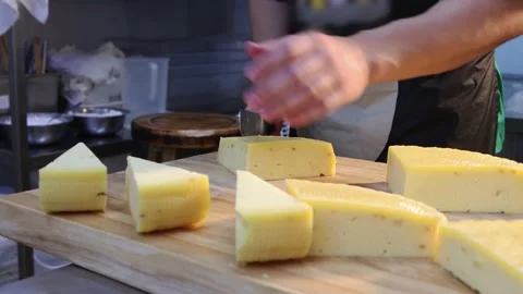 Restaurant serving - man cutting off triangle pieces of cheese with a knife Stock Footage 160078676