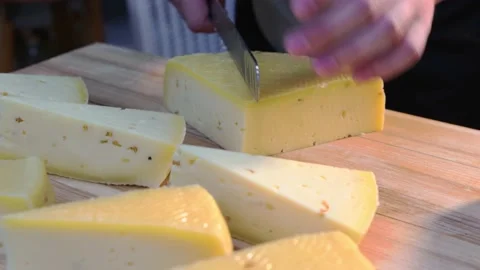Restaurant serving - man cutting off triangle pieces of cheese with a knife on Stock Footage 160079008