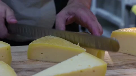Restaurant serving - man worker cutting off triangle pieces of cheese with a Stock Footage 160079145