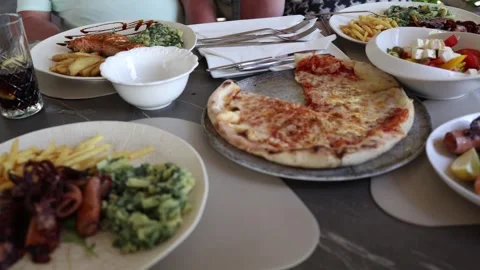 Restaurant table filled with pizza salmon squid fries salad and seafood during a Stock Footage 341558395