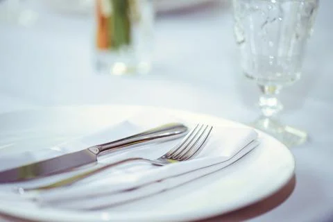 Restaurant table setout with white plates and silverware. Stock Photos