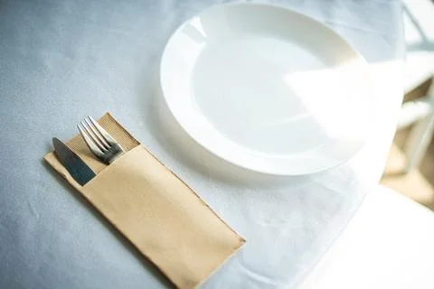 Restaurant table setting with white plate and cutlery Stock Photos