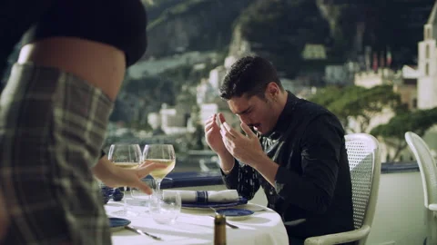 At restaurant with view of coast in the background, a cheating boyfriend sitting Stock Footage 199459020