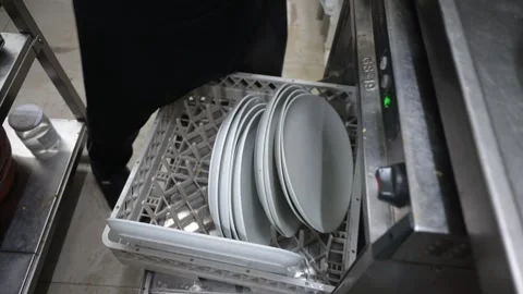Restaurant worker loading plates into a commercial dishwasher Stock Footage 323792586