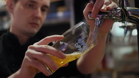 A restaurant worker pours draft beer into a glass from a tap Stock Footage 307088344