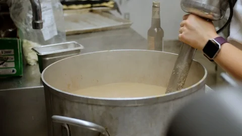 Restaurant Worker Stirs Huge Steaming Pot with Industrial Mixer, 4k Stock Footage 125788807