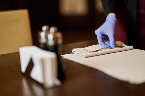 Restaurant worker using gloves for setting up tables Stock Photos