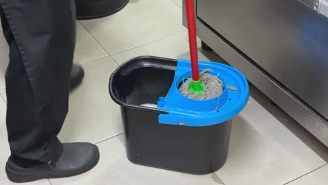 Restaurant worker wringing out a mop in a bucket Video stock 344100330