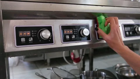 Restaurant workers hand carefully wiping a stainless steel industrial stove with Stock Footage 318317261