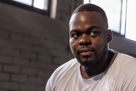Resting after intense training, man wearing white athletic T-shirt sweating in Stock Photos