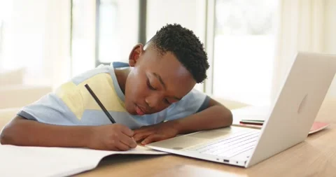 Resting arm on table, African American boy scribbling with pencil and viewing Stock Footage 336305867