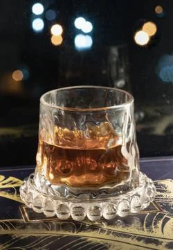 Resting gracefully upon a beaded glass coaster, a whiskey glass glows with .. Foto stock