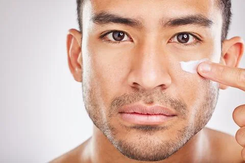 Resting hunk face. Cropped studio portrait of a young man applying moisturiser Stock Photos