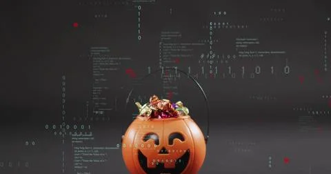 Resting orange jack-o'-lantern bucket holding foil candies on glossy tabletop, 库存照片