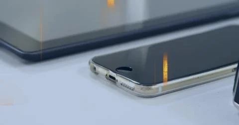 Resting phone with home button scuffed clear case and charging port on white Stock Photos