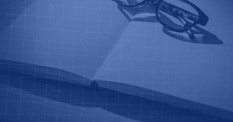 Resting rectangular eyeglasses casting shadows on open paper on desk with grid Foto stock