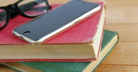 Resting smartphone with clear case reflecting light on wood table, showing worn Stock Photos