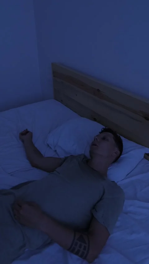 Restless man lying awake in bed at night, struggling to fall asleep from Видео 346244404