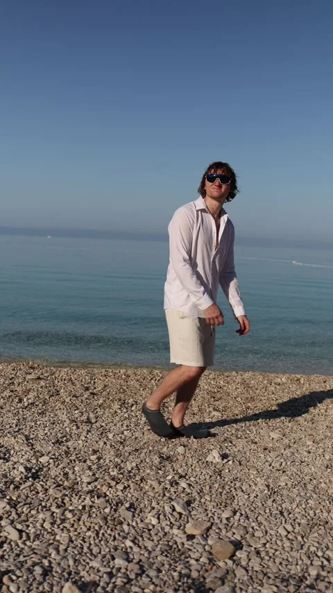 Restless man walks on beach during vacation unable to slow down and simply enjoy Stock Footage 341621795
