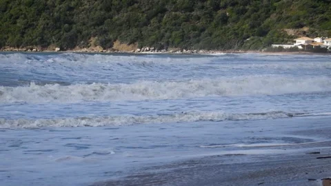 Restless Ocean Waves Crashing on Sandy Beach with Green Hills Stock Footage 323591188