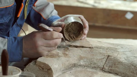 The restorer introduces the cement mortar by a small spatula into the cracks Stock Footage 119488573
