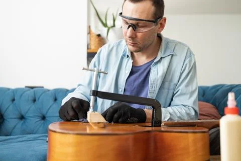 Restring classical guitar concept. The man repair an old guitar. Stock Photos