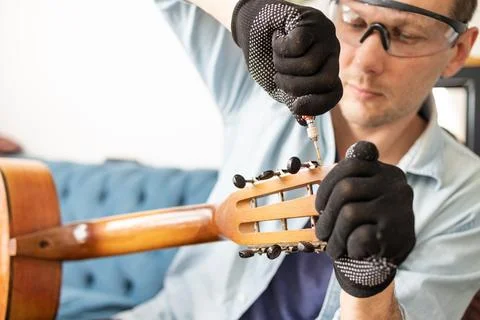 Restring classical guitar concept. The man repair an old guitar. Stock Photos