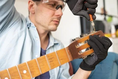 Restring classical guitar concept. The man repair an old guitar. Stock Photos