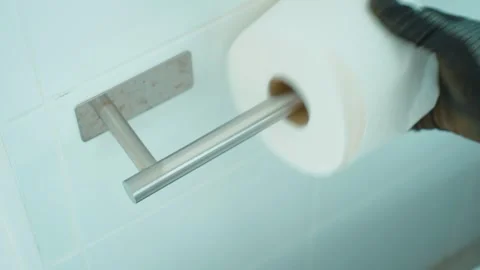 Restroom cleaner reaching for empty toilet paper tube while servicing bathroom Stock Footage 345125813