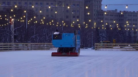 Resurfacing machine cleaning ice of open air skating rink in slow motion Stock Footage 101687740
