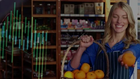 Retail clerk arranging oranges, offering one to camera as graphs rising on Stock Footage 330509364