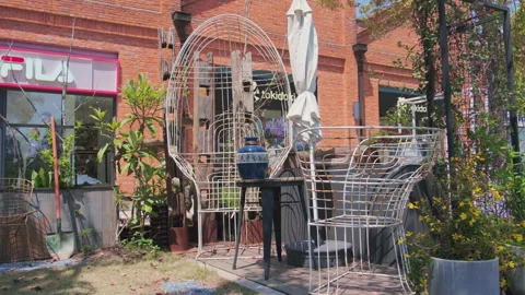 Retail patio with white wire seating outside red brick storefronts, daytime Stockbeeldmateriaal 332852275