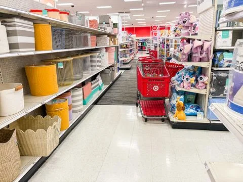 Retail store aisle featuring storage baskets, bins, and red shopping carts .. Stock Photos