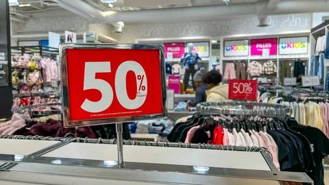 Retail store interior featuring 50 off sale sign with clothing racks and Stock Photos