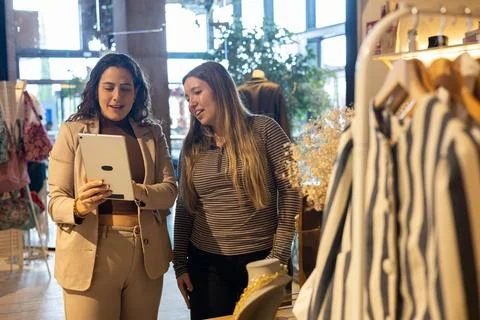 Retail worker helping customer with digital tablet in boutique Fotos de archivo