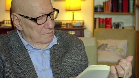 Retired elderly sitting alone at home reading a book Stock Footage 74437526
