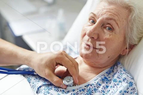 Retired female looking at camera while doctor examining her Stock Photos