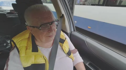 Retired grey haired man in glasses and yellow vest in car Stock Footage 146324571