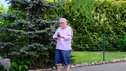 Retired man extends long black selfie stick with smartphone Stock Footage 135443194