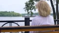 Retired man hugging wife sitting on park bench near river, senior couple rest 4k or 4k+ Resolution