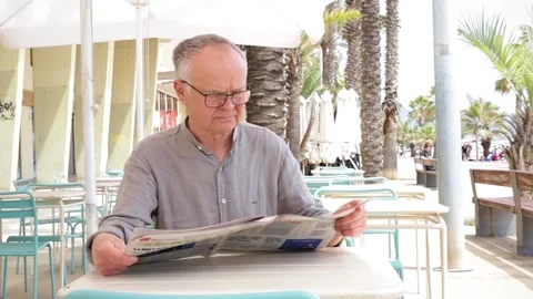 Retired man sitting with newspaper Stock Footage 309803492