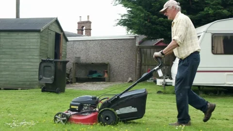 Retired middle aged man cutting the grass, gardening, mowing the lawn Stock Footage 197129806