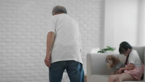 A retired old man uses a vacuum cleaner to clean the floors, with a young gra Stock Footage 153445765