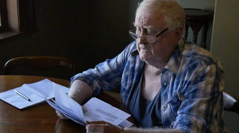 Retired pensioner at table stressed looking at debt Stock Footage 67340410