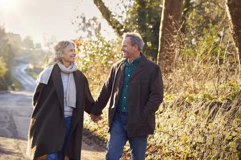 Retired Senior Couple Enjoying Winter Walk Through Village In Countryside Stock Photos