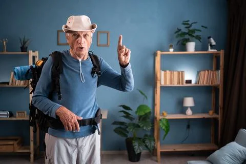 Retired traveler with backpack doing idea gesture at home. Tourist makes active Stock Photos